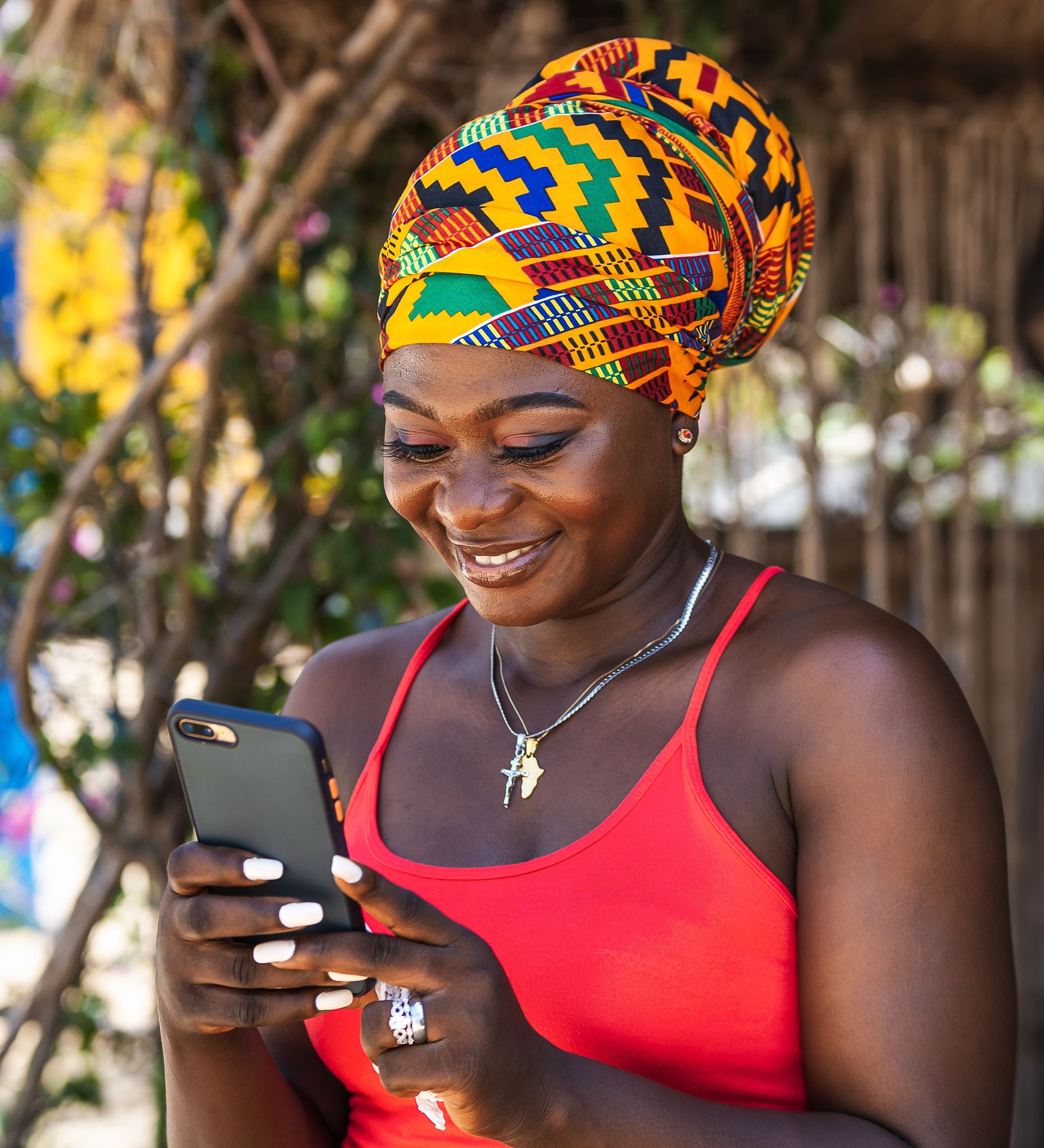 African woman happily chatting on social media in a tropical village in Ghana
